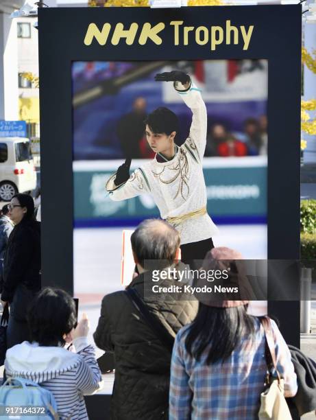 Photo taken on Nov. 10 shows people taking photos of a poster of figure skater Yuzuru Hanyu displayed outside the venue of the NHK Trophy in Osaka....