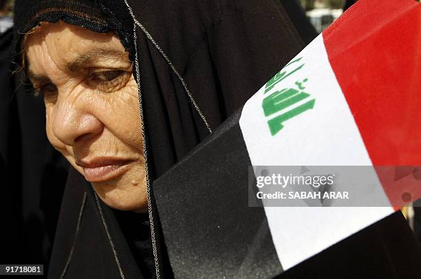 An Iraqi woman hold her national flag as she takes part in a demonstration against a plan by MPs to adopt a closed voting system during the upcoming...