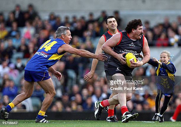 Robert DiPierdomenico attempts to evade a tackle by Dwayne Lamb and Maddy Mainwaring during the Chris Mainwaring charity AFL match at Subiaco Oval on...