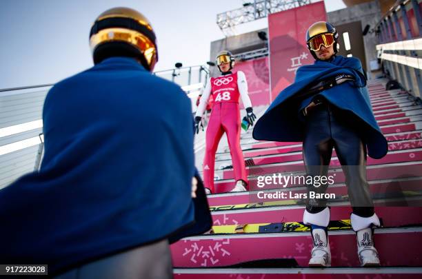 Fabian Riessle of Germany tries to keep warm at the Normal Hill next to his team mates Johannes Rydzek and Eric Frenzel during the Nordic Combined...