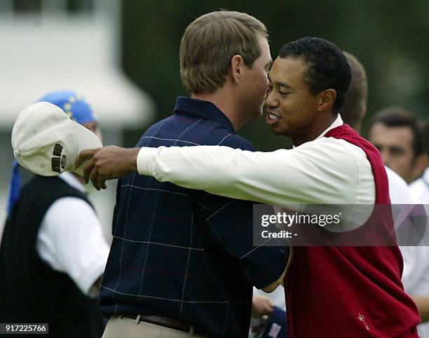 Tiger Woods of the US hugs teammate Davis Love the III on the 18th green after their fourball match victory against European's Sergio Garcia and Lee...