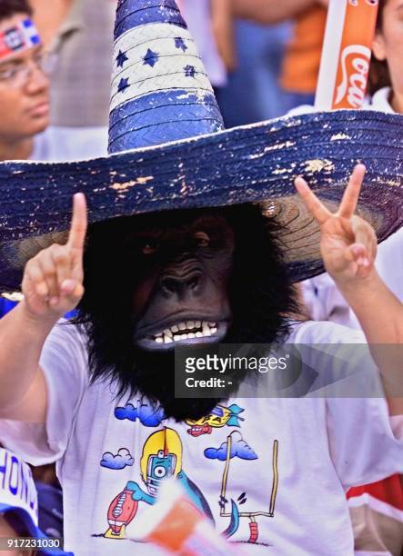 Fan of the Honduran soccer team, disguised with a mask and and a hat makes the sign of "two to one" in reference to the result he hopes his team will...