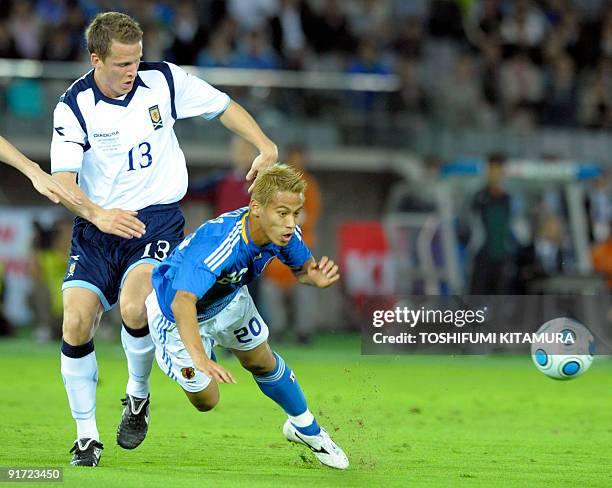 Japan's midfielder Keisuke Honda watches the ball while fighting with Scotland's defender Christophe Berra during their Kirin Challenge Cup football...
