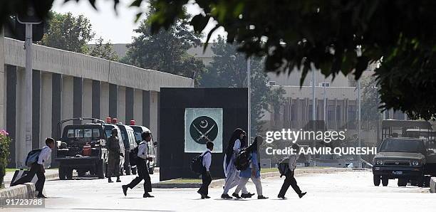 Pakistani schoolchildren walk past the main entrance of Pakistan�s army headquarters after a heavily armed militant attack in Rawalpindi on October...