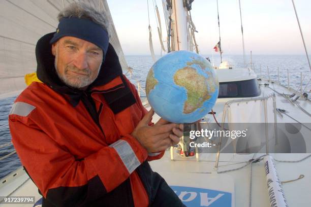 Le navigateur Jean-Luc Van Den Heede pose avec un globe terrestre sur son bateau, à l'aube du 06 octobre 2002 au large des côtes bretonnes. Le marin...