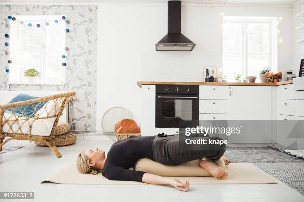 real woman at home in kitchen doing yoga and meditation - bolster stock pictures, royalty-free photos & images