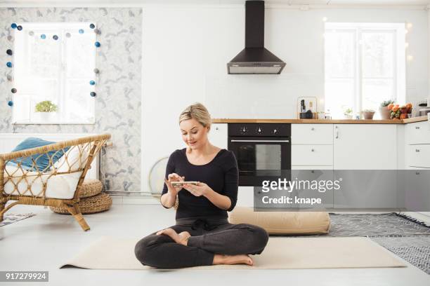 real woman at home in kitchen doing yoga and meditation - bolster stock pictures, royalty-free photos & images