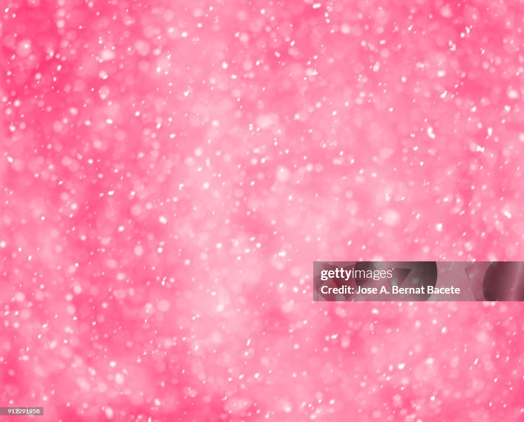 Background of snowflakes of snow that fall down from the sky on a light pink bottom. Spain