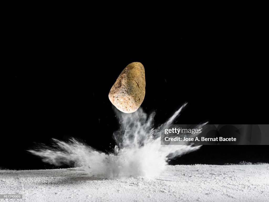 Impact of meteorite, rock or stone of fire on the soil, producing an explosion and a crater of powder on a black background. Spain