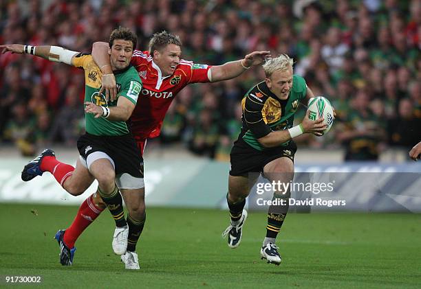 Shane Geraghty of Northampton breaks away from Jean de Villiers as Northampton's Ben Foden assists during the Heineken Cup match between Northampton...