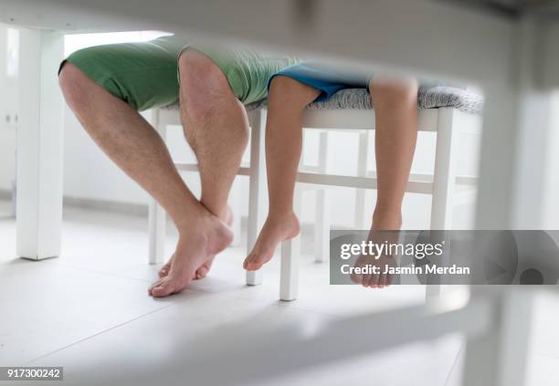 father and son at new home sitting on chair in dining room - legs on the table foto e immagini stock