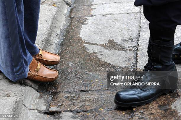 Picture showing the shoes of a soldier and of the wife of ousted Honduran President Manuel Zelaya, Xiomara Castro, as she stands on the sidewalk's...