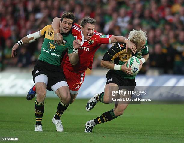 Jean de Villiers of Munster attempts to stop Shane Geraghty and Ben Foden during the Heineken Cup match between Northampton Saints and Munster at...