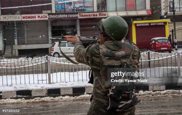 An Indian paramilitary trooper aims his gun towards Kashmiri civilians watching a gun battle between Indian government forces and suspected militants...