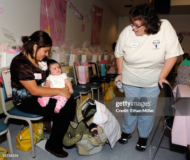 Valerie Gomez holds her two month-old daughter Eliana Gomez as Soldiers' Angels volunteer Windy McWeeney looks on during a baby shower held at Nellis...