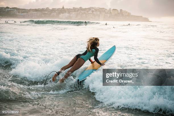 woman surfer jumps in the waves - bondi stock pictures, royalty-free photos & images