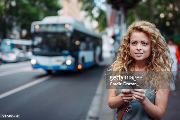 frau, mit mobilen app auf bushaltestelle - sydney bus stock-fotos und bilder