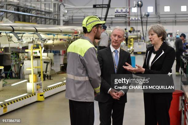 British Prime Minister Theresa May speaks to a worker, accompanied by Michael Ryan , president of Bombardier Aerostructures and Engineering services...