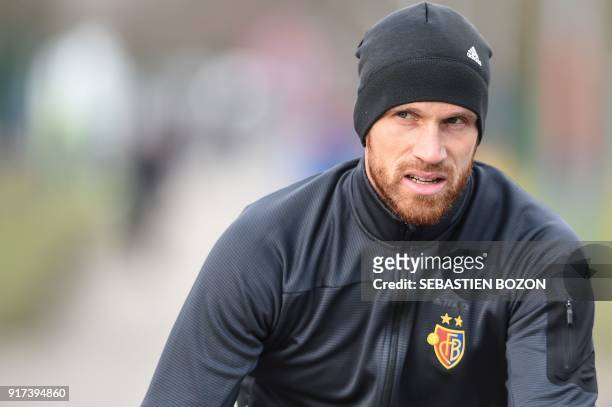 Basel's Swiss defender Michael Lang rides a bike as he arrives for a training session on February 12 in Basel, on the eve of the UEFA Champions...
