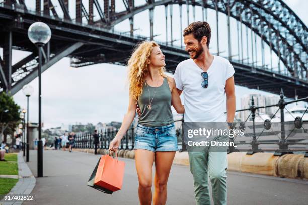 in de zomer met boodschappentassen (echt) paar - sydney harbour bridge stockfoto's en -beelden