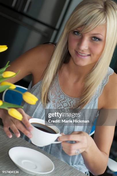 young adult blonde woman lifting up a cup of coffee. - marie hickman all images stock pictures, royalty-free photos & images