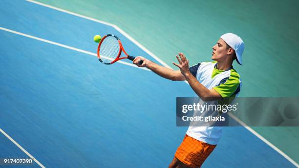 junger mann mit dem tennisspielen. - tennis action stock-fotos und bilder