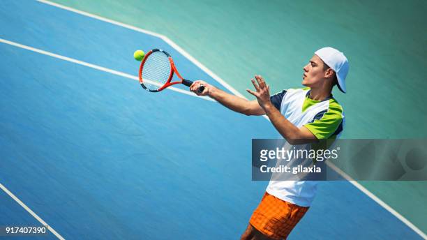 young man playing tennis. - blue tennis racket stock pictures, royalty-free photos & images