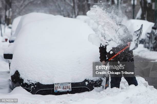 Jordan Weagley shovels snow surrounding his car in the 2600 block of North Fransisco Avenue following several inches of overnight snowfall on Sunday,...