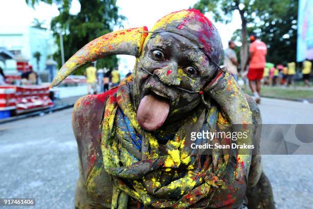 Carnival revelers with his face covered in paint and wearing horns poses for a portrair during the J'ouvert street procession as part of Trinidad...