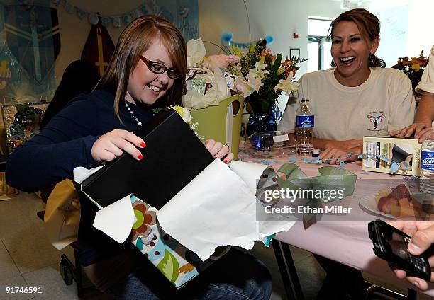 Erin Couts unwraps gifts as volunteer Laura Herbst from the National Charity League looks on during a baby shower held at Nellis Air Force Base for...