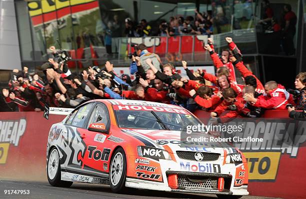 Garth Tander driver of the Holden Racing Team Holden is congratulated by his team after he and teammate Will Davison won the Bathurst 1000, which is...