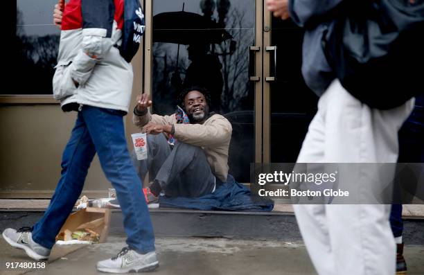 Man waves to people taking part in the second annual Winter Walk to end homelessness as they march past on Boylston Street in Boston on Feb. 11, 2018.