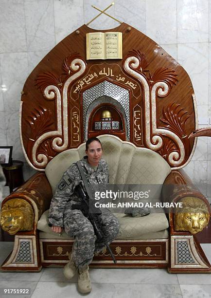 Soldier poses for a picture as she sits on a chair that belonged to executed Iraqi dictator Saddam Hussein at the former presidential palace, which...