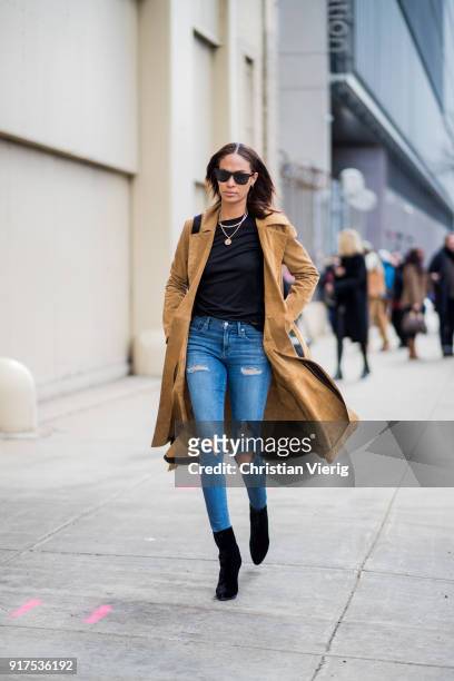 Model Joan Smalls wearing brown trench coat, blue ripped denim jeans, black ankle boots seen outside Ralph Lauren on February 12, 2018 in New York...