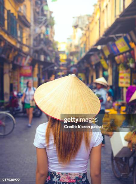 rear view of a vietnamese women with conical hat in a street of hanoi in vietnam - sombrero asiático fotografías e imágenes de stock