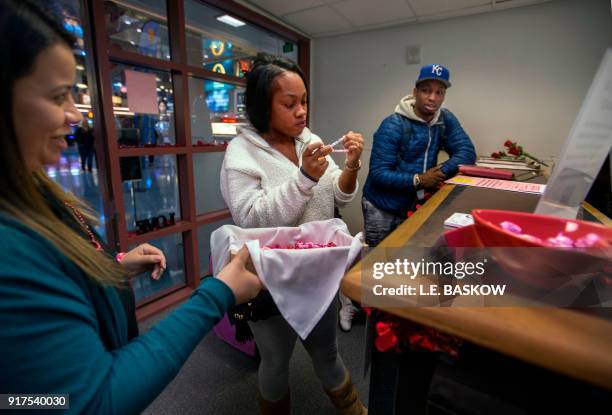 Employee Bianca Dozal offers a bracelet gift to Teaira Thompson and James Anderson of Burlington, Iowa, who completed their paperwork as the Clark...