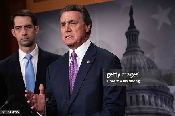 Sen. David Perdue speaks as Sen. Tom Cotton looks on during a news conference on immigration February 12, 2018 at the Capitol in Washington, DC....