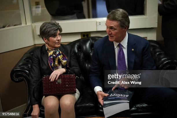 Sen. David Perdue holds up a copy of President Donald Trump's FY2019 budget proposal as Sen. Joni Ernst looks on prior to a news conference on...