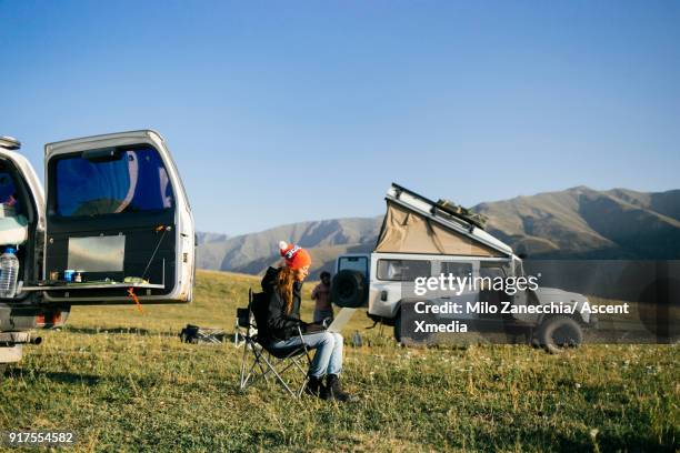 woman working on computer while 4x4 camping in mountain meadow - mongolian women stock pictures, royalty-free photos & images