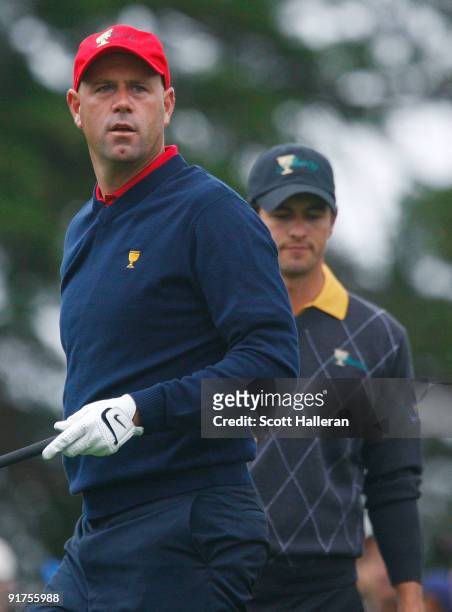 Stewart Cink of the USA Team watches his tee shot on the second hole as Adam Scott of the International Team looks on during the Final Round Singles...