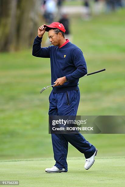 Team member Tiger Woods takes off his cap after making his final putt on the 13th green to win his match against Y.E. Yang of South Korea and clinch...