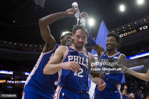 Joel Embiid and Robert Covington of the Philadelphia 76ers pour water on T.J. McConnell after McConnell recorded a triple double against the New York...
