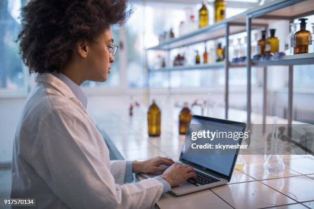 african american female biotechnologist working on laptop in a laboratory. - forensic science lab stock pictures, royalty-free photos & images