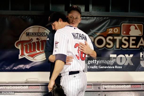 Pitcher Joe Nathan of the Minnesota Twins is comforted by teammate Justin Morneau after being defeated by the New York Yankees in Game Three of the...