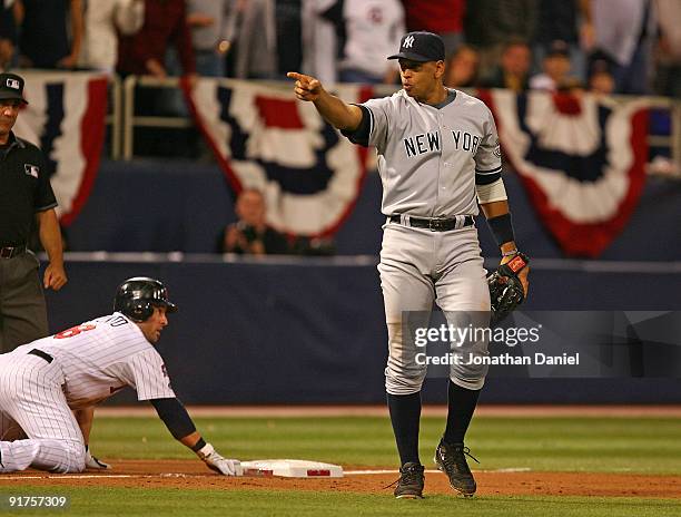 Alex Rodriguez of the New York Yankees points to teammate Jorge Posada after he tagged out Nick Punto of the Minnesota Twins in Game Three of the...