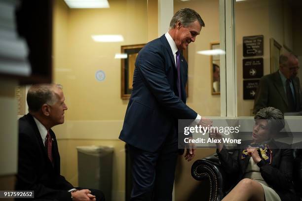 Sen. David Perdue fist-bumps Sen. Joni Ernst as Sen. Thom Tillis looks on prior to a news conference on immigration February 12, 2018 at the Capitol...