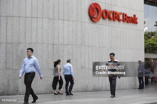 Pedestrians walk past an Oversea-Chinese Banking Corp. Logo displayed outside the company's branch in the central business district of Singapore, on...