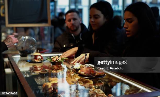 People at a restaurant enjoy appetizer and snack in Spanish cuisine; 'Tapas' in Madrid, Spain on February 12, 2018. With it's rich varieties, Spain's...