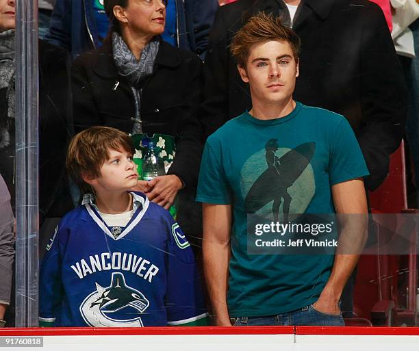 Zac Efron stands beside a young fan as he watches the Vancouver Canucks play the Dallas Stars at General Motors Place on October 11, 2009 in...