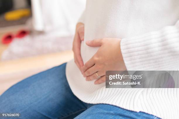 pregnant woman touching abdomen - asian woman pregnant stock pictures, royalty-free photos & images